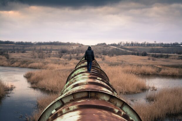 A man walking along a pipeline