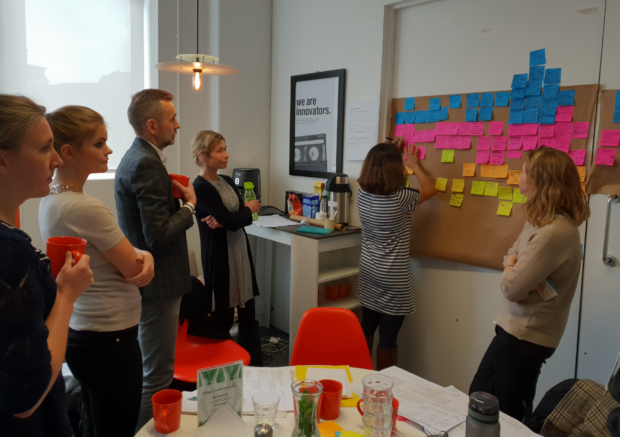 People standing in a meeting room with post-it notes on a board