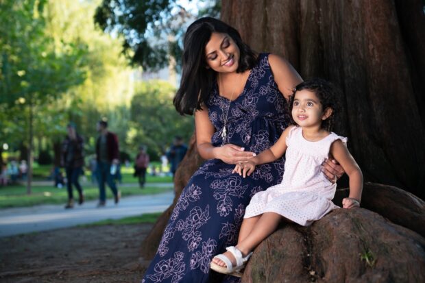 A mother and daughter sat on a large tree root